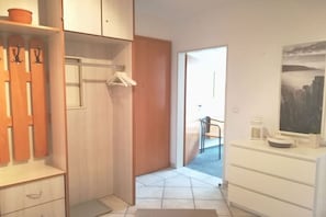 A room with a wooden wardrobe, a white dresser, a painting on the wall, and a door leading to another room. - Holiday apartment with 2 bedrooms (Seebad Heringsdorf)