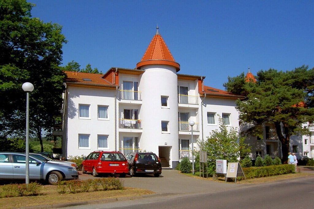 A multi-story building with a central cylindrical tower and a red-tiled roof.