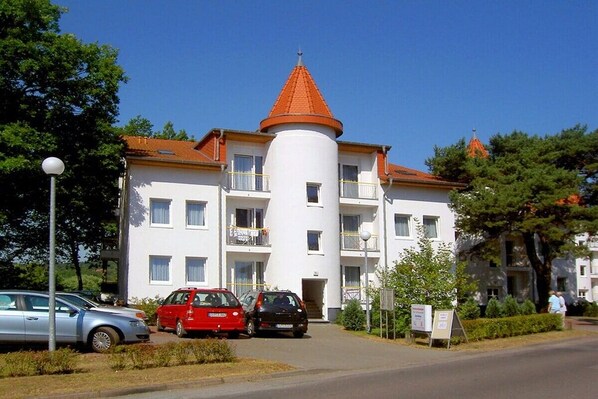 Un edificio a più piani con una torre cilindrica centrale e un tetto in tegole rosse.