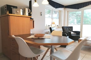 A dining area with a wooden table, white chairs, and a black leather chair. - Holiday apartment with 2 bedrooms (Seebad Heringsdorf)