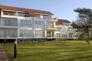 Un edificio residenziale a più piani con balconi, tetto piano e un prato curato.
