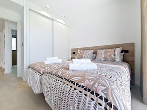 A modern bedroom with a large bed, a wooden headboard, and a walk-in closet. - Ground Floor Apartment Overlooking the Pool (Los Alcazares)