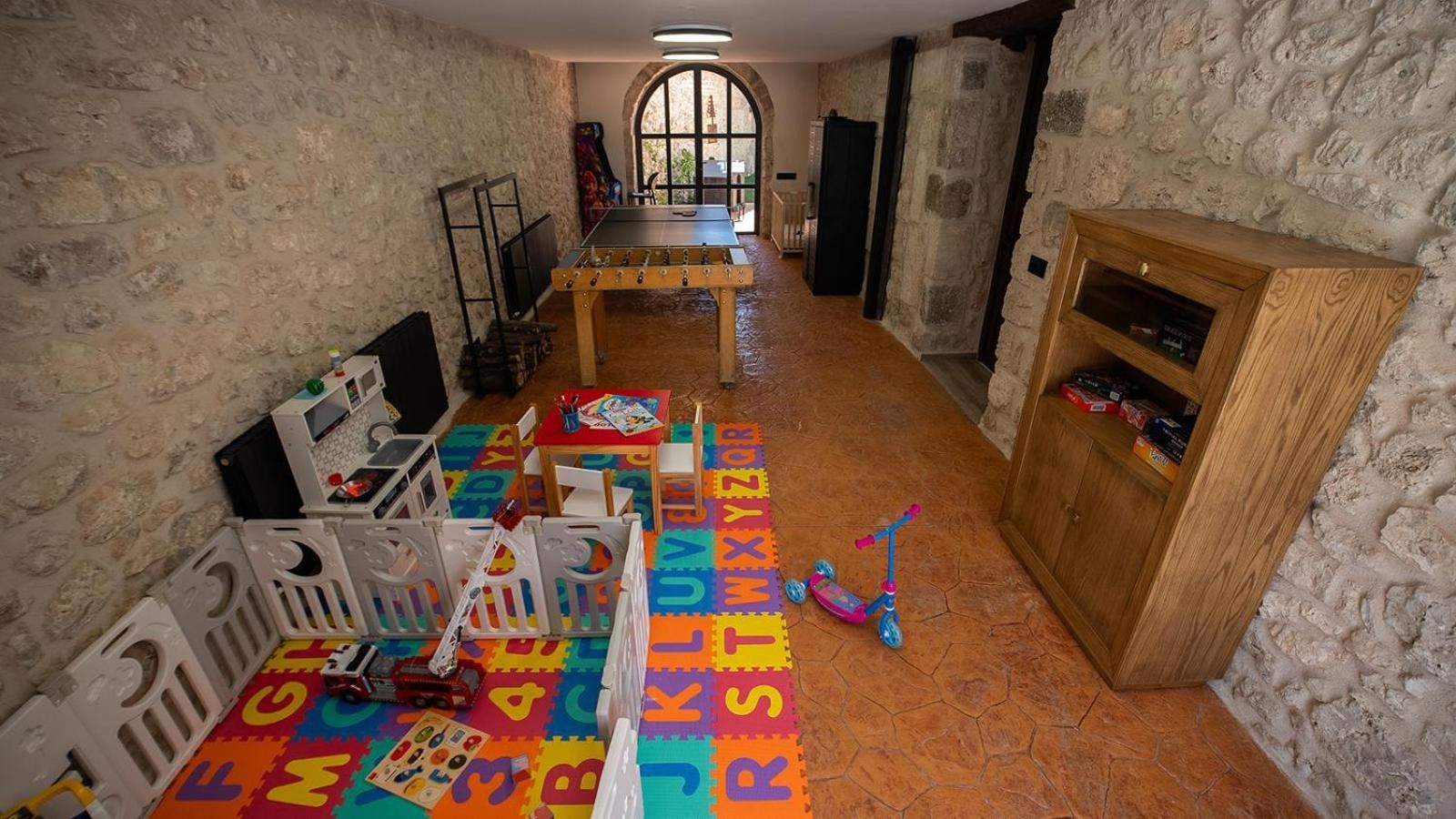 Een speelkamer met een zachte, schuimende vloer, speeltoestellen en een houten kast.