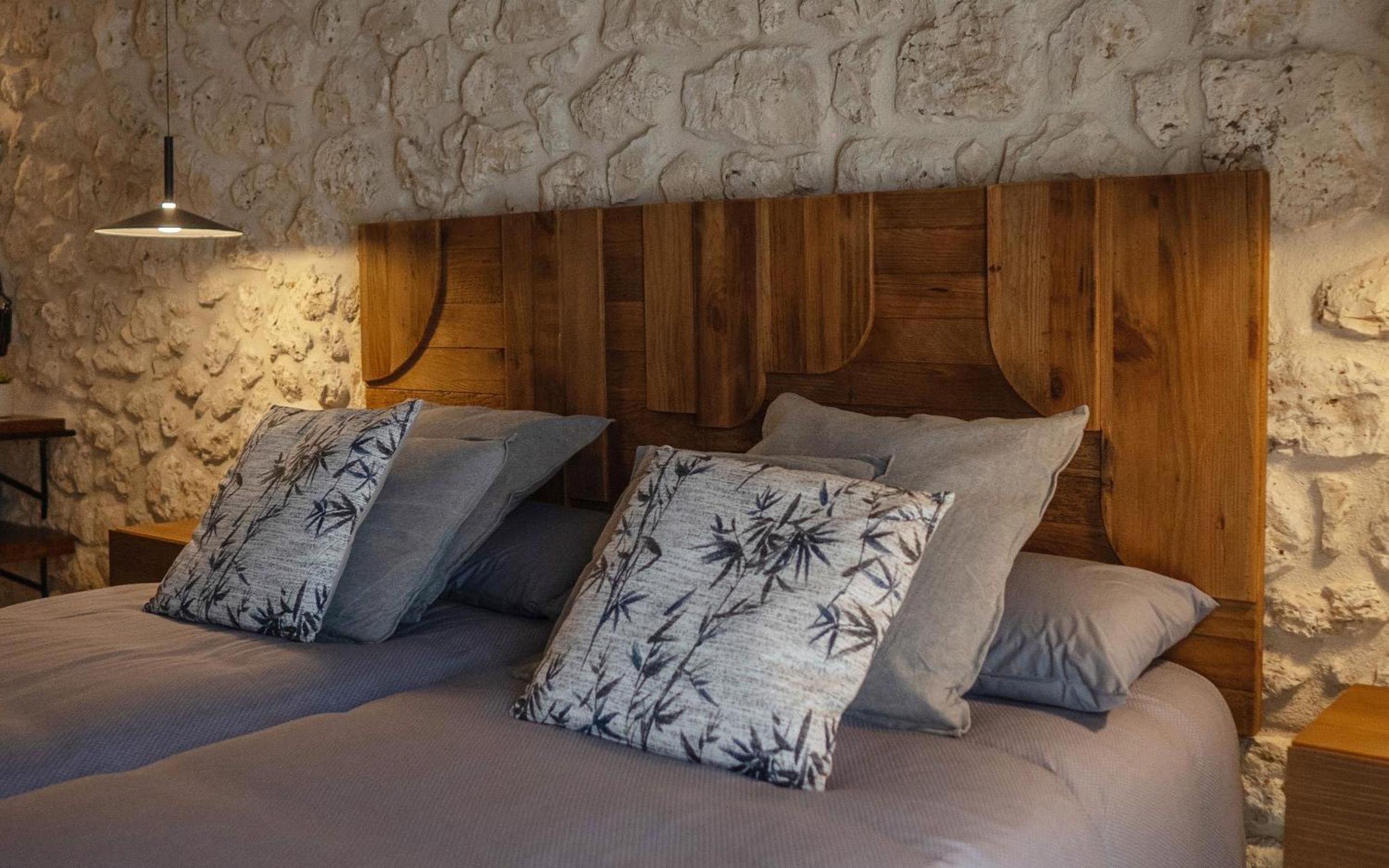 A bed with a wooden headboard and two pillows with a bamboo pattern.