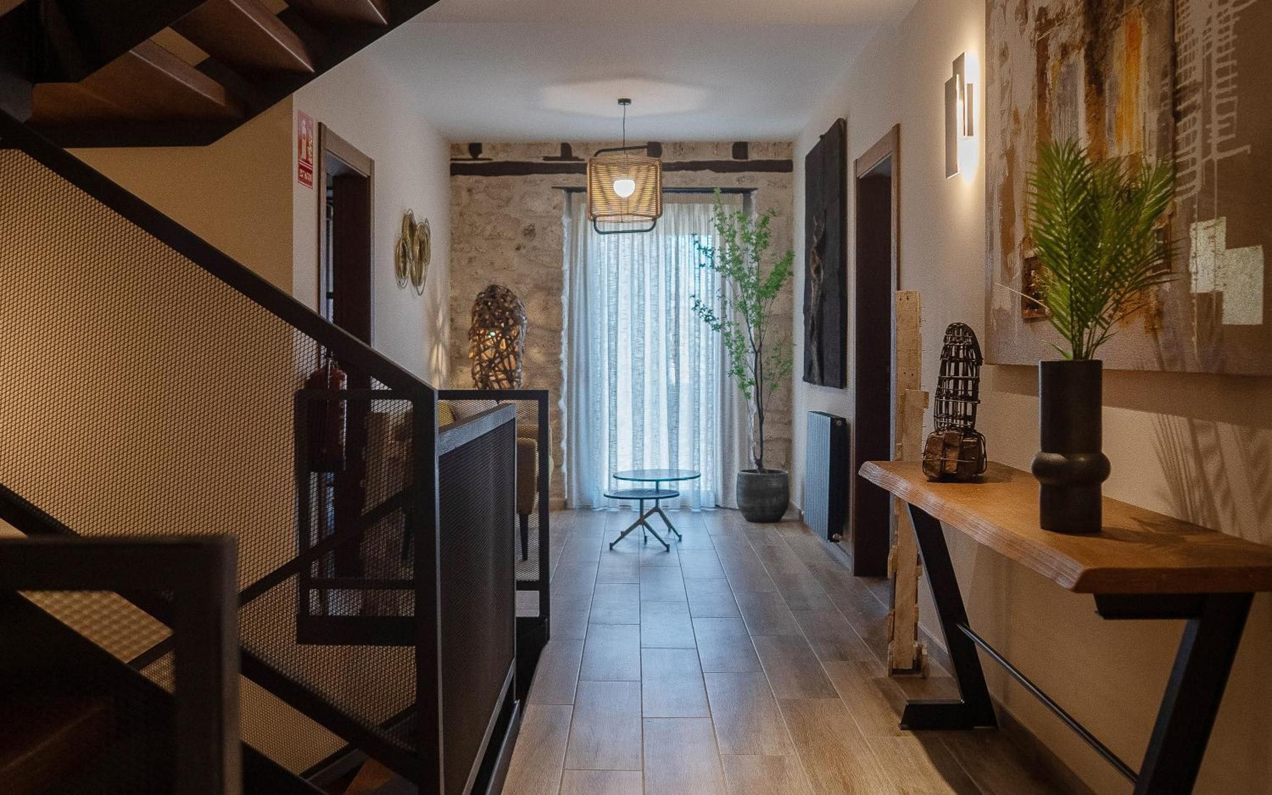 A hallway with a staircase, a round table, and a potted plant.
