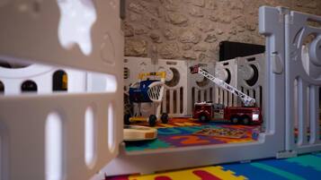 A play area with a toy fire truck, a toy ladder, and a toy market stall.