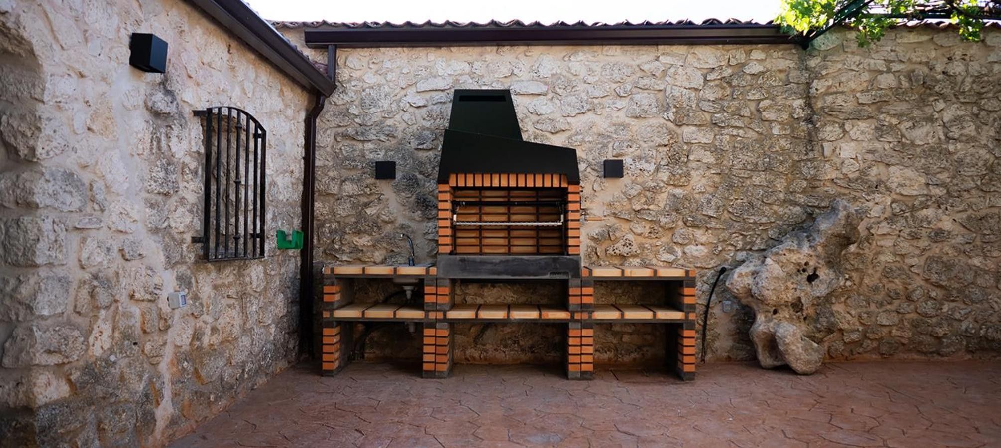 A stone wall with a brick barbecue grill.