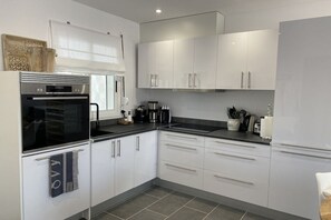 A modern kitchen with white cabinets, a black countertop, and stainless steel appliances. - Casa Blanka Bahia Playa (Costa Calma)