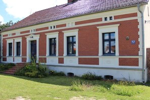 A two-story building with a red brick facade and white trim around the windows and doors. - Blue holiday apartment (Michendorf)