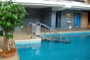An indoor swimming pool with a tiled floor, a potted plant, and a metal staircase leading into the pool. - Holiday apartment with 2 bedrooms (Bad Herrenalb)