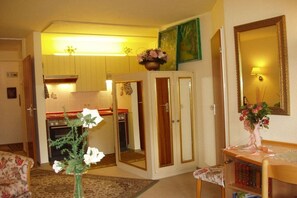 A room with a kitchen area, a mirror, and a vase with flowers. - Holiday apartment with 2 bedrooms (Bad Herrenalb)