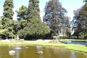 Ein Park mit Teich, Bänken und Bäumen.