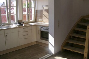 A kitchen with white cabinets, a stove, and a window with a view of a backyard. - Holiday apartment with 2 bedrooms (Waren-Müritz)