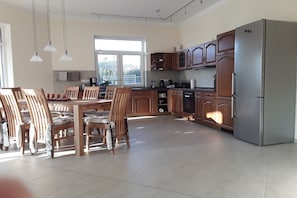 Een moderne keuken met houten kastjes, een roestvrijstalen koelkast en een eethoek met houten stoelen en een tafel.