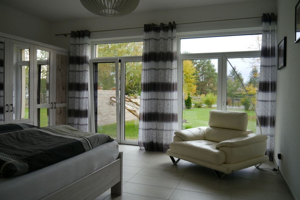 A bedroom with a bed, a chair, and a view through a glass door to the outside.