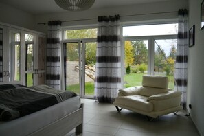Een slaapkamer met een bed, een stoel en uitzicht door een glazen deur.