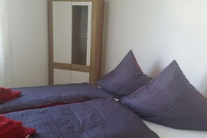 Un dormitorio con cama, almohadas, un armario y un espejo.