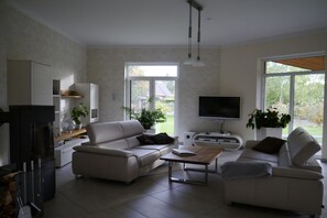 Ein modernes Wohnzimmer mit Kamin, zwei Sofas, einem Couchtisch und einem Flachbildfernseher.