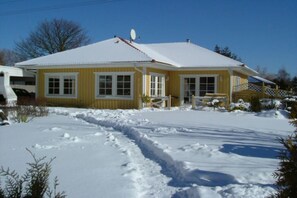 Ein gelbes Haus mit verschneitem Dach und blauem Himmel.