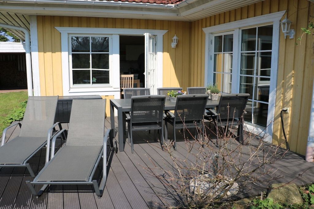 A deck with outdoor furniture, including chairs and a table, and a small garden area with a plant.