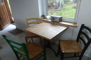 Spiseplads med et bord og fire stole, en radio på en hylde og et vindue med udsigt til det fri.