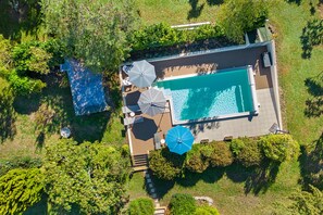 An aerial view of a swimming pool with adjacent umbrellas and a small deck area. - Holiday Home 'Maison Joie de Vivre' with Large Fenced Garden, Private Pool, Terraces and AC (Cénac-et-Saint-Julien)