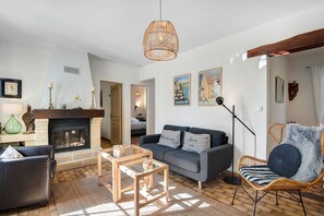 Uma sala de estar com lareira, sofá, mesa de centro e uma poltrona de vime.