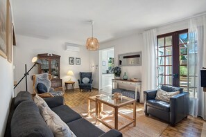 A living room with a sofa, armchairs, a coffee table, and a dining area with a chair and table. - Holiday Home 'Maison Joie de Vivre' with Large Fenced Garden, Private Pool, Terraces and AC (Cénac-et-Saint-Julien)
