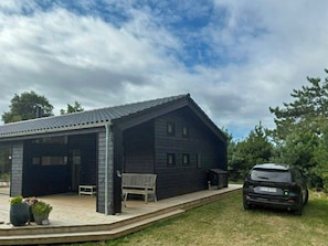 Een modern huis met een overdekte patio, een auto op de oprit en een gazon.