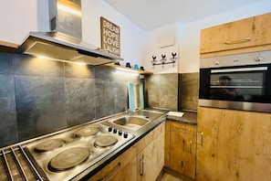 A modern kitchen with a gas stove, stainless steel appliances, and wooden cabinets. - Superior apartment Goldener Hahn (Baiersbronn)
