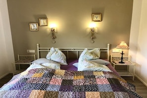 A bed with a quilt, two bedside tables, wall-mounted lamps, and framed pictures. - Superior apartment Goldener Hahn (Baiersbronn)