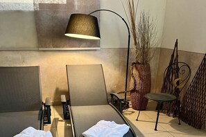 A room with a sofa, a chair, a lamp, a vase with plants, and a metal railing. - Superior apartment Goldener Hahn (Baiersbronn)