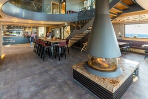 A modern interior with a central fireplace, a bar area, and a staircase leading to an upper level. - Superior apartment Goldener Hahn (Baiersbronn)
