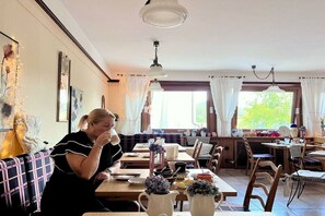 Ein Essbereich mit Tischen, Stühlen und einer Person, die an einem Tisch sitzt.