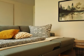 Ein Wohnzimmer mit einer Couch, Kissen, einem gerahmten Kunstwerk und einem kleinen runden Tisch.