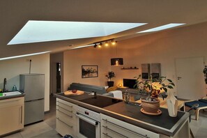 Eine moderne Küche mit Oberlicht, eingebauten Geräten und einer Essecke mit Sofa und Tisch.