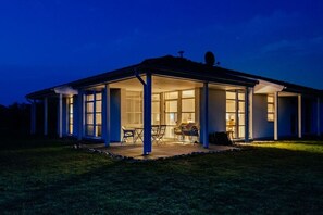 Ein Haus mit überdachter Terrasse, großen Fenstern und einer Satellitenschüssel.