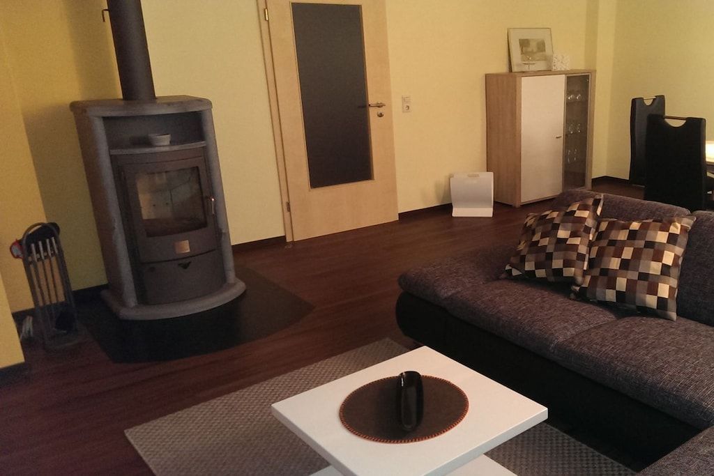 A living room with a wood-burning stove, a sofa, a cabinet, and a small table.