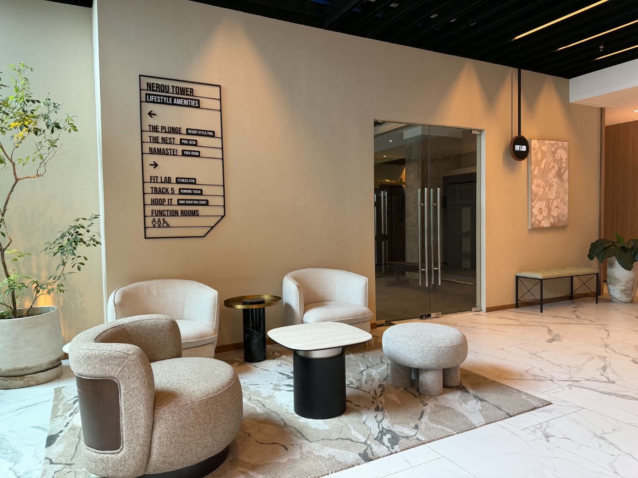 Un hall d’entrée moderne avec un panneau d’orientation, un espace détente et une grande plante en pot.