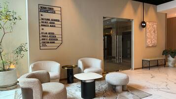 A modern lobby with a directional sign, seating area, and a large potted plant.