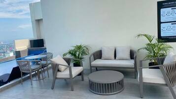 A rooftop terrace with outdoor seating, a pool, and a city view.