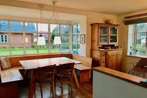 Ein Essbereich mit einem Holztisch und Stühlen, einer Bank und einem Holzschrank mit Glastüren.