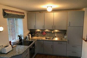 A kitchen with granite countertops, a built-in oven, a sink, and a window with a view. - Holiday apartment with 2 bedrooms (Norddorf)