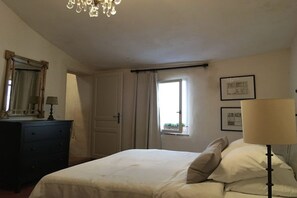A bedroom with a bed, a dresser, a mirror, a window with curtains, and a chandelier. - Holiday home in Le Barroux with Wi-Fi (Le Barroux)