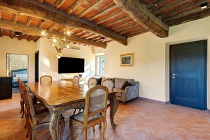 A dining area with a wooden table and chairs, a chandelier, and a sofa. - Holiday Home 'Villa Roncacccio' with Mountain View, Wi-Fi and Air Conditioning (Borgo a Mozzano)