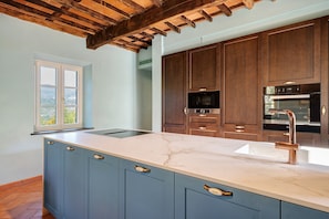 A kitchen with a marble countertop, wooden cabinets, and a built-in oven. - Holiday Home 'Villa Roncacccio' with Mountain View, Wi-Fi and Air Conditioning (Borgo a Mozzano)