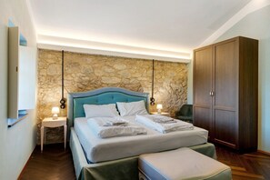 Ein Schlafzimmer mit Steinsturz, einem Bett mit weißen Leinen, einem Holzschrank und einem Nachttisch mit Lampe.