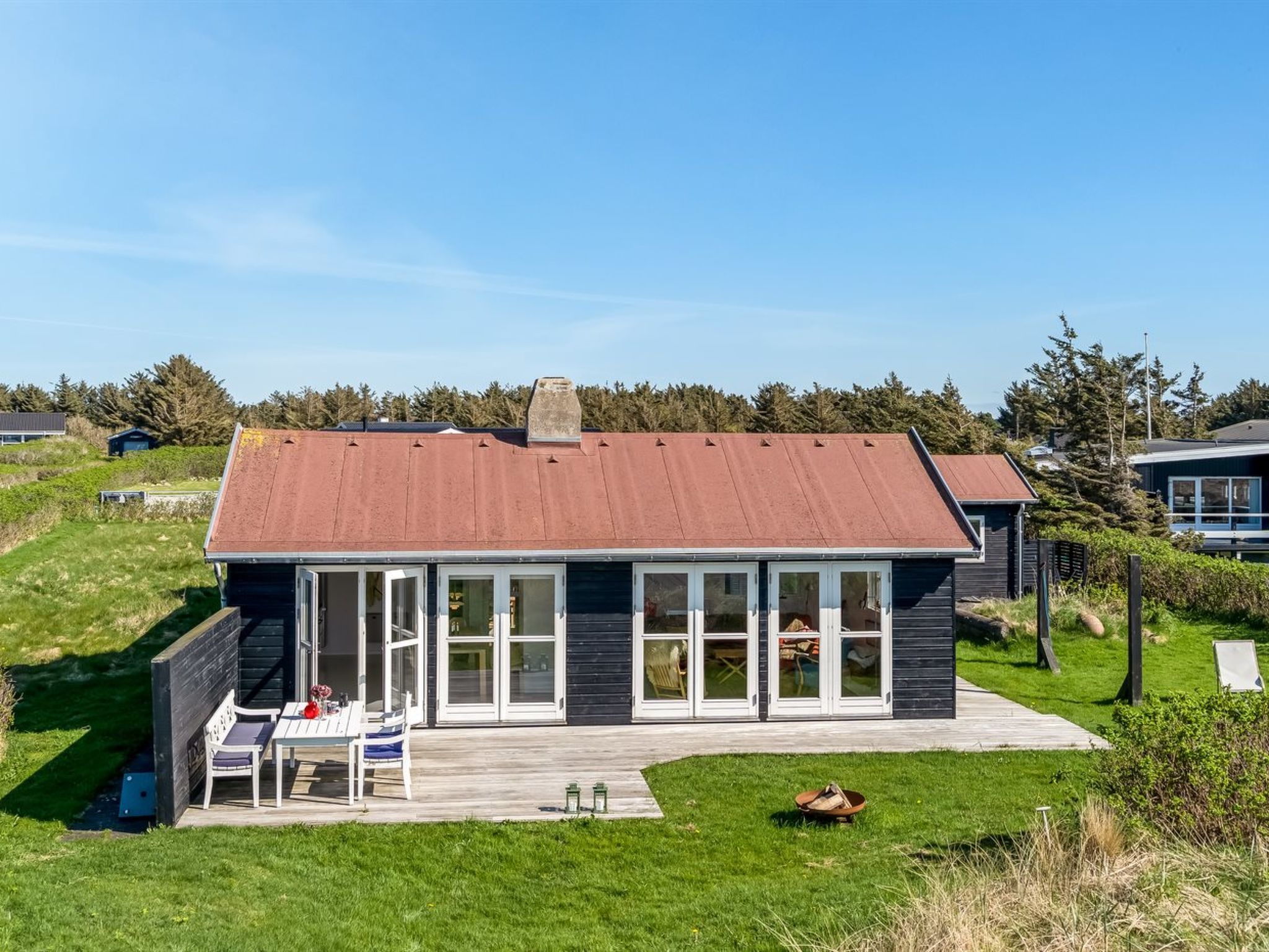 A modern house with a large deck, a chimney, and a view of the surrounding landscape.
