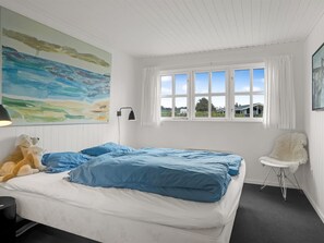 A bedroom with a bed, a window, a chair, and a painting on the wall. - "Aaran" - 100m from the sea by Interhome (Løkken)