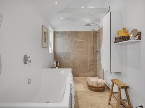 A modern bathroom with a large bathtub, a shower area, and a wooden stool. - "Aaran" - 100m from the sea by Interhome (Løkken)